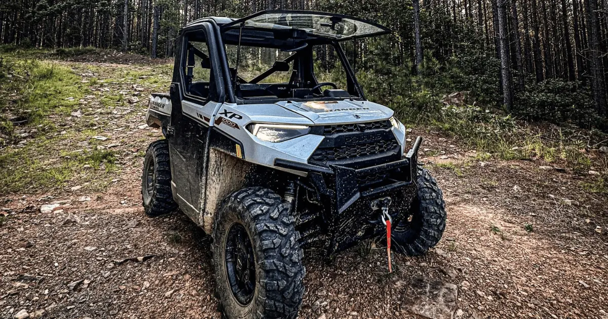 A custom Polaris Ranger covered in mud, deep in the woods