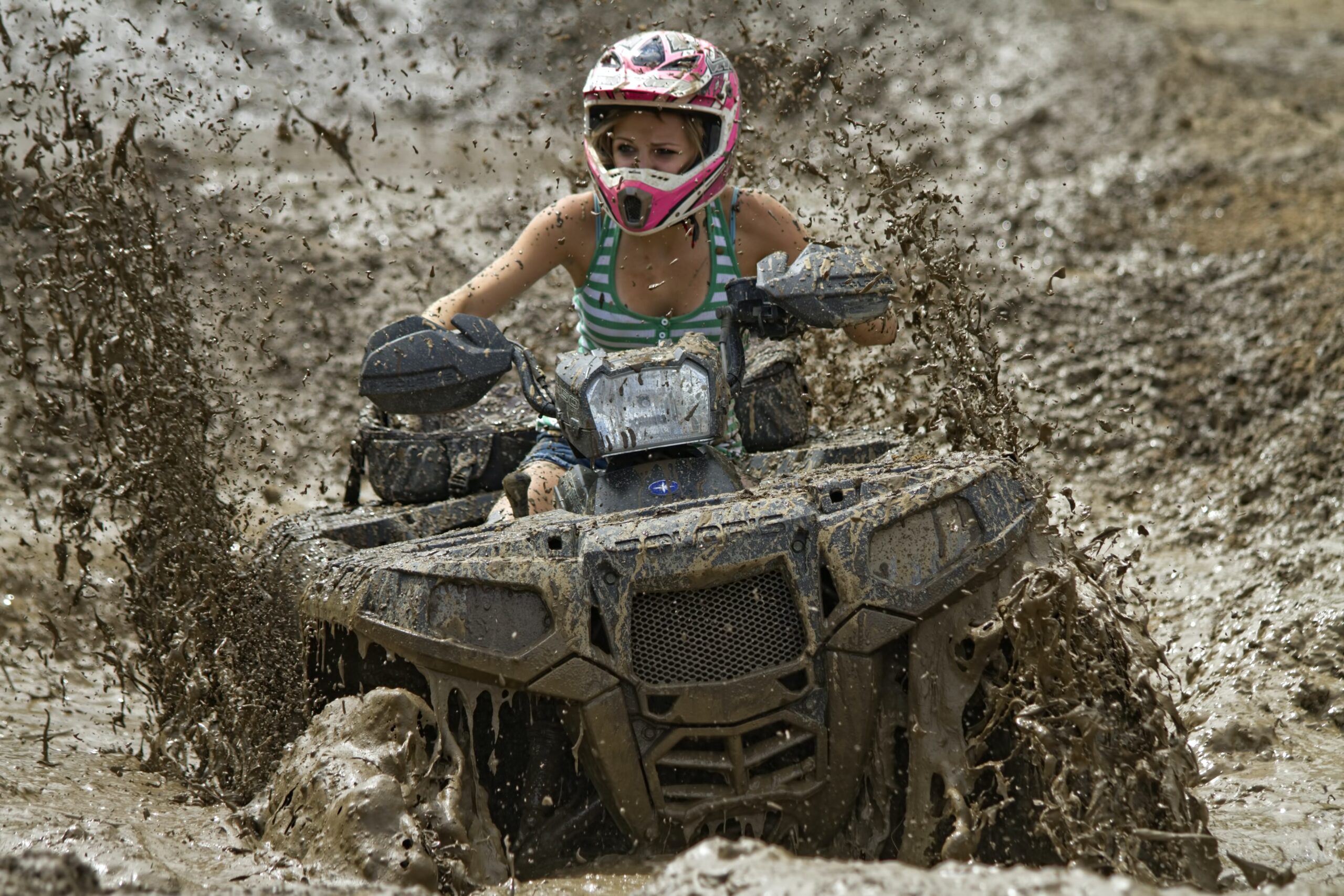 This is a woman riding a Polaris Ranger 500 through a deep mud hole.