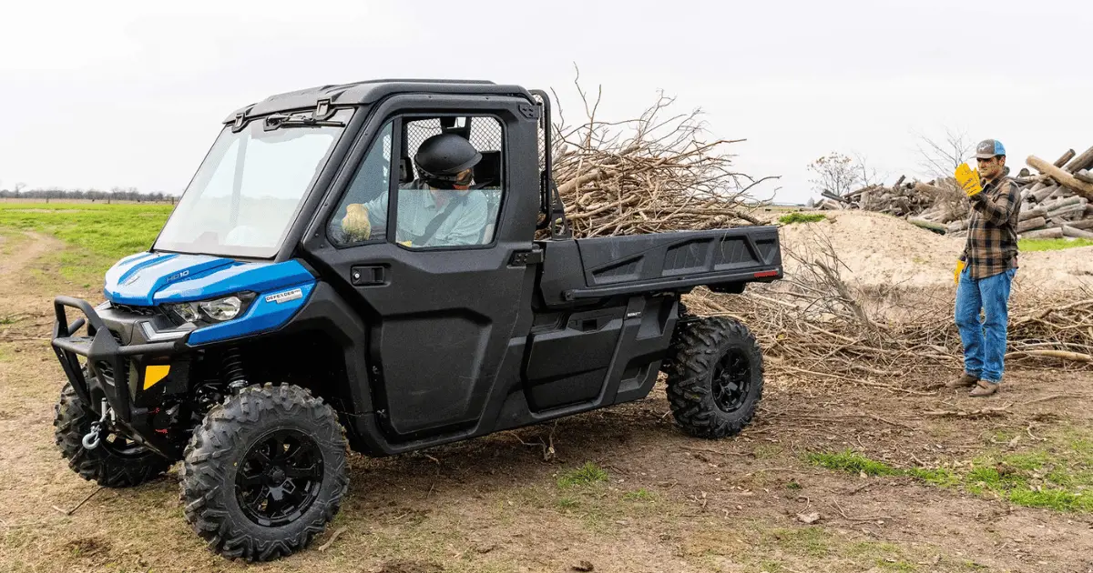 A Can-Am Defender on a farm being used to haul lumber
