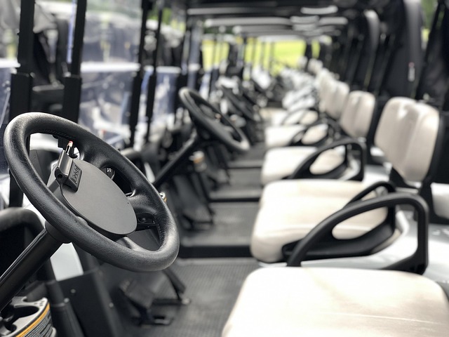 Row of modern golf carts with steering wheels and beige seats lined up at golf course rental area