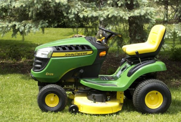 John Deere D125 riding lawn mower with yellow seat and mower deck on green grass