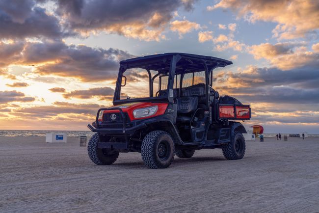 Kubota RTV-X1140 utility vehicle on the beach at sunset with cargo bed and off-road tires