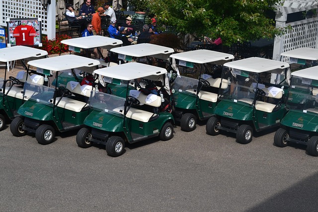Row of EZGO green golf carts lined up at a golf tournament with sun canopies and golf bags