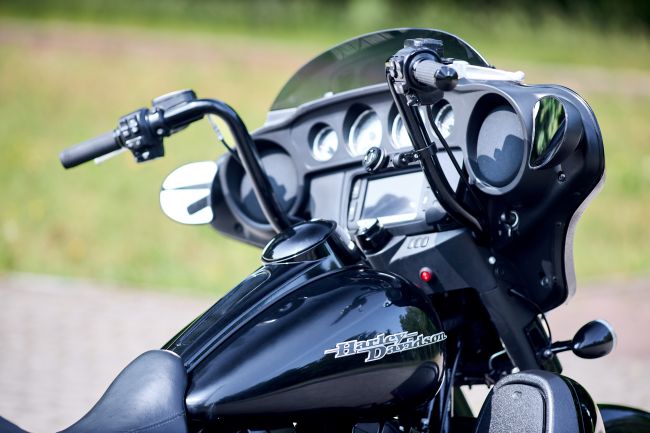 Black Harley-Davidson touring motorcycle with windshield, gauges, and custom handlebars