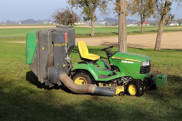 John Deere X540 lawn tractor with rear grass collector and yellow mower deck working on a field