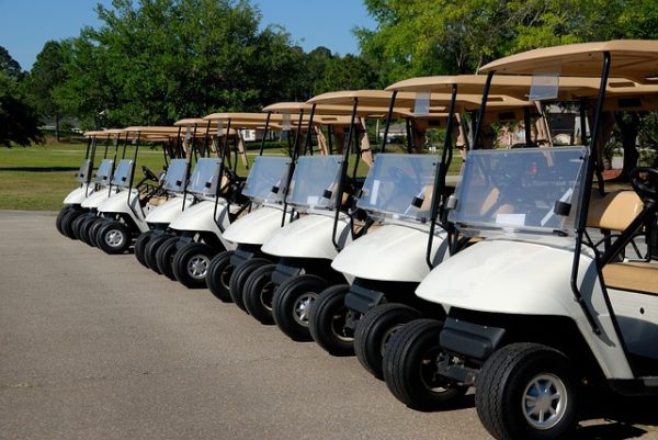 golf-carts-parked-at-golf-course Row of golf carts lined up at a golf course parking area