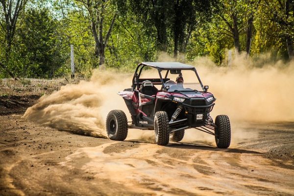 Polaris RZR side-by-side kicking up dust on an off-road trail
